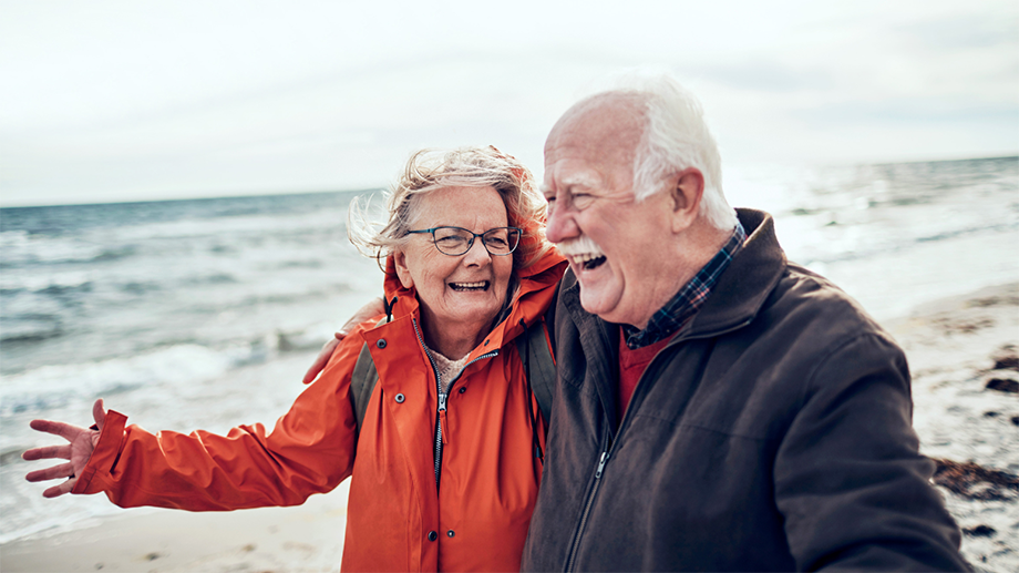 Photo of elderly man and woman on the beach, smiling